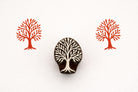 Hand carved wooden tree stamp with branching silhouette printed in red ink on textured paper