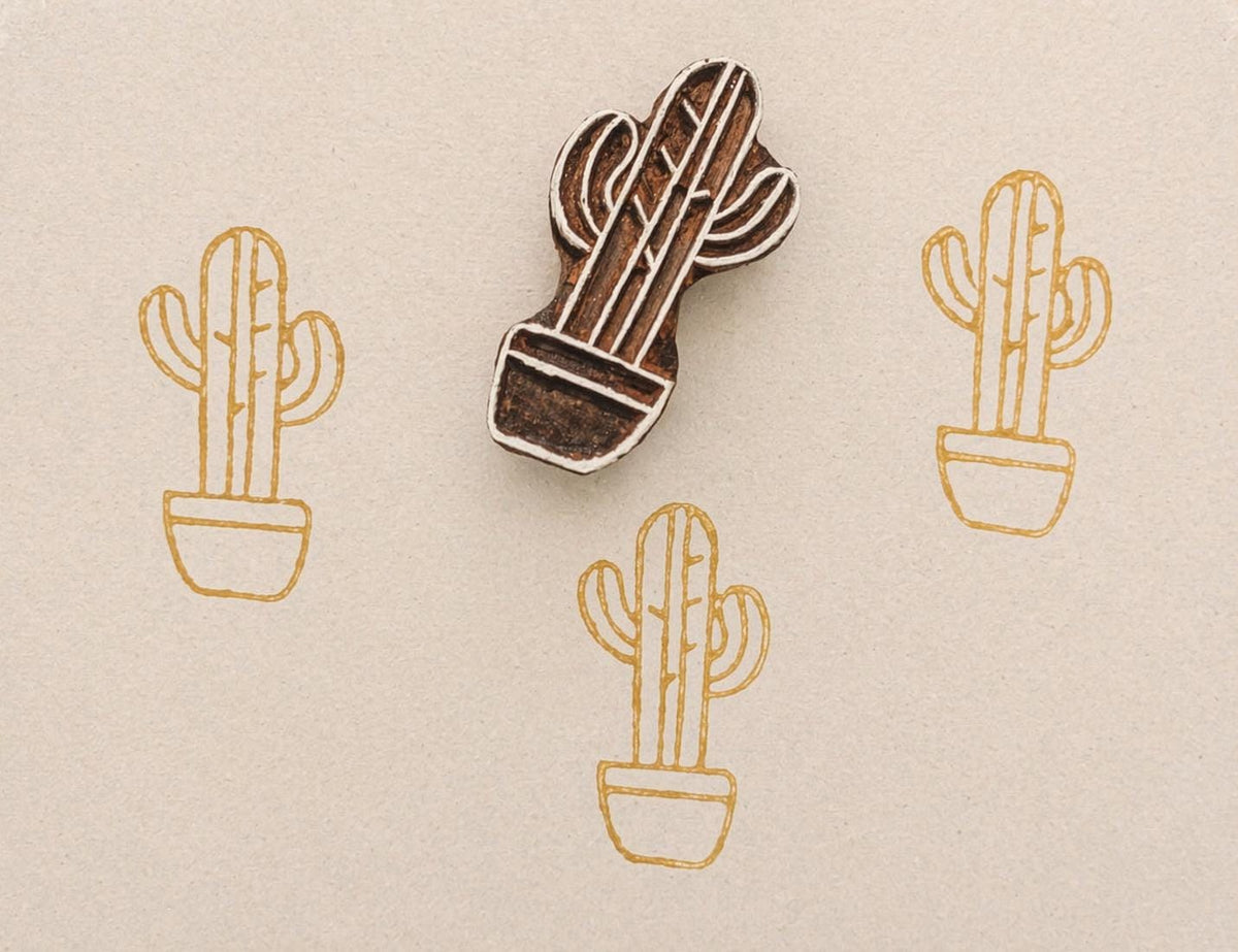 Hand carved cactus stamp printing repeating gold cactus pattern on neutral paper