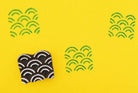 Wooden wave pattern stamp with green ink pattern on bright yellow background