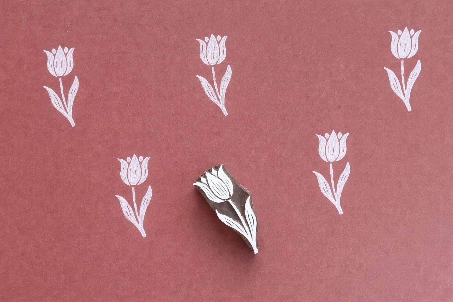 Tulip wood block printing stamp creating repeating floral pattern on fabric or paper