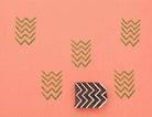 Hand-carved chevron pattern stamp with repeated zigzag print on coral background