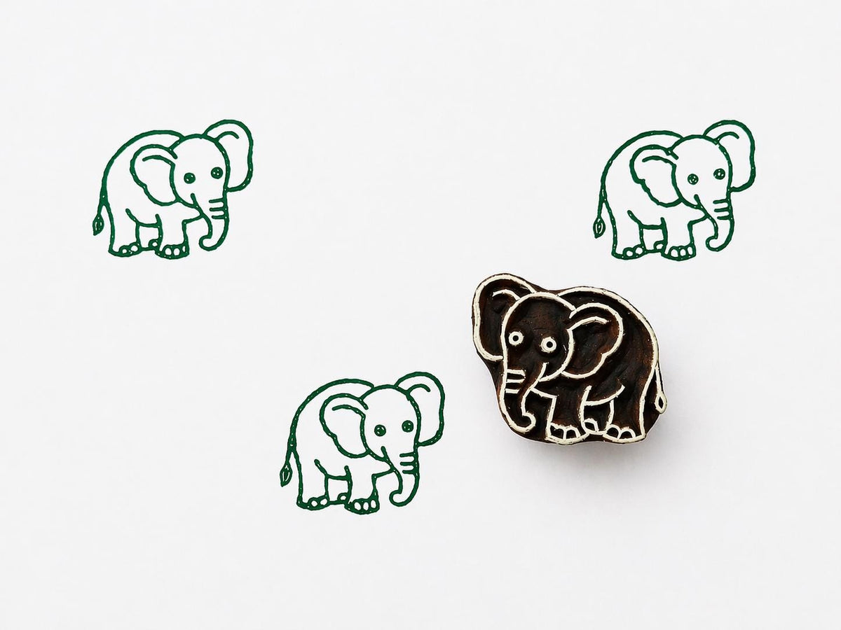 Hand carved wooden elephant printing stamp with repeated green elephant impressions on white background, cute safari animal design for textile printing