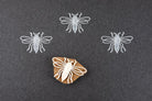 Hand carved wooden block print stamp with bee design creating repeating insect pattern on dark background