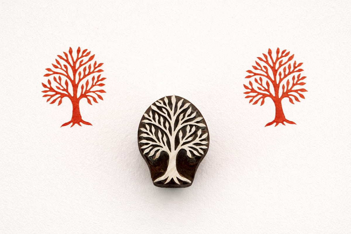 Hand carved wooden stamp featuring a classic leafy tree design with red printed impressions on white background