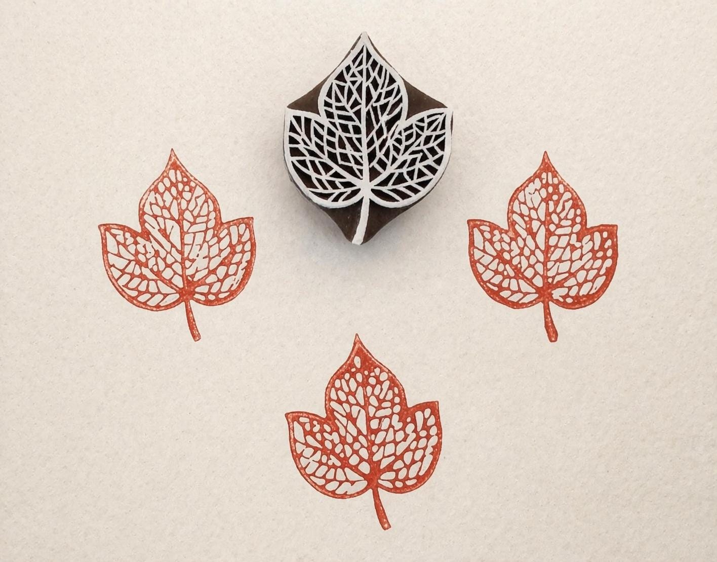 Hand carved Indian wooden printing block featuring triple peepal leaf cluster design creating detailed orange botanical prints on fabric