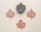 Hand carved Indian wooden printing block featuring triple peepal leaf cluster design creating detailed orange botanical prints on fabric