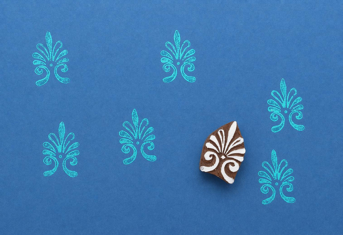 Hand-carved block print stamp with an abstract ornamental pattern repeated on a blue background