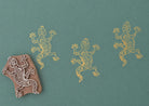 Hand carved Indian wooden block printing stamp with lizard design used for fabric, textile, clay, and pottery printing on green background.
