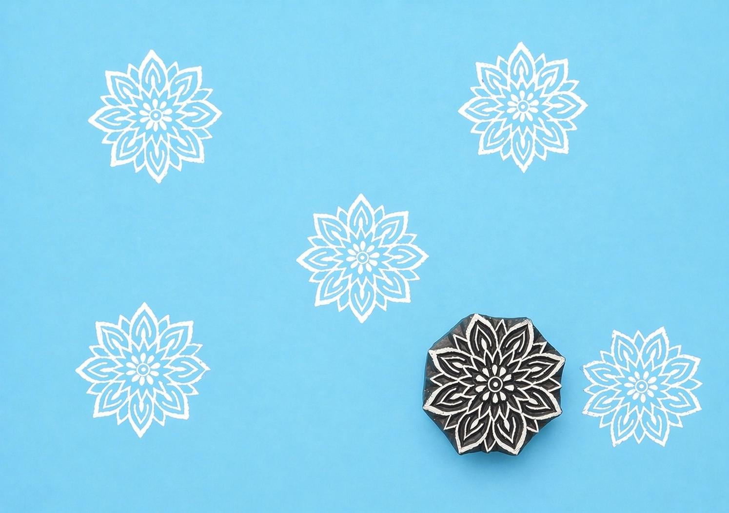 Hand carved Indian wooden printing block featuring mandala floral design creating white symmetrical pattern on blue fabric
