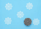 Hand carved Indian wooden printing block featuring mandala floral design creating white symmetrical pattern on blue fabric