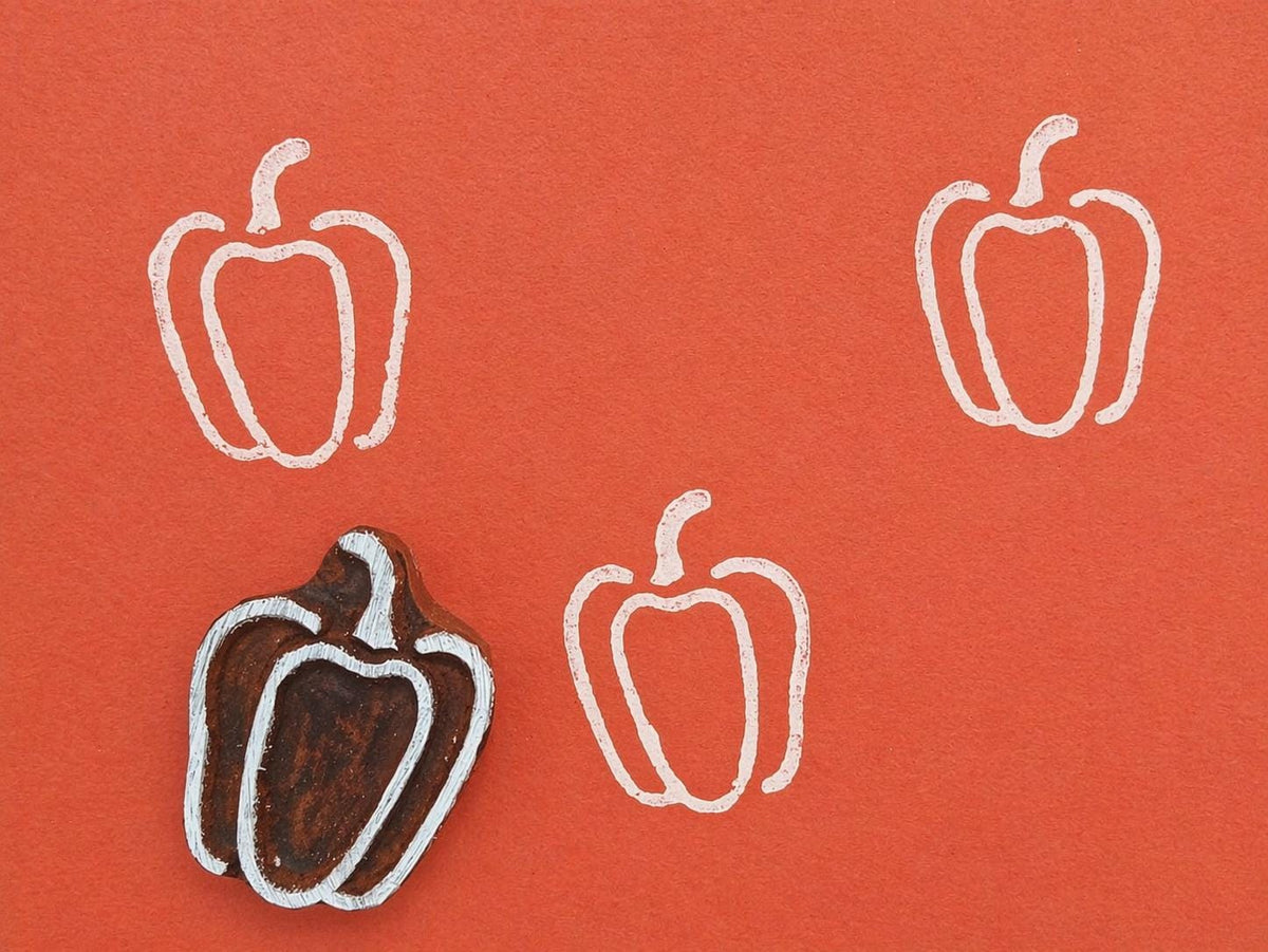 Hand carved pepper stamp printing white pepper pattern on orange background