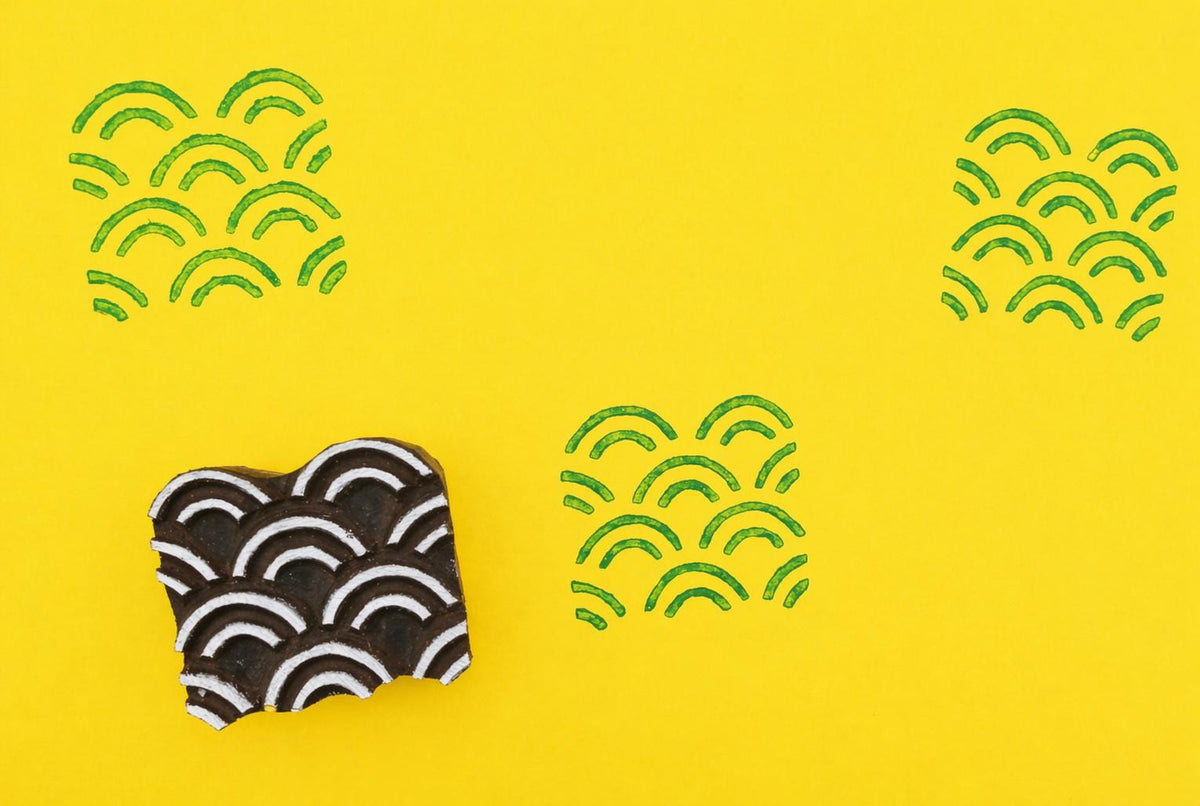 Wooden wave pattern stamp with green ink pattern on bright yellow background