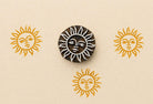 Sun face wooden stamp creating repeated golden sun prints on neutral paper