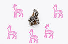Hand carved wooden block stamp creating a Scandinavian folk style deer pattern with floral details in pink ink