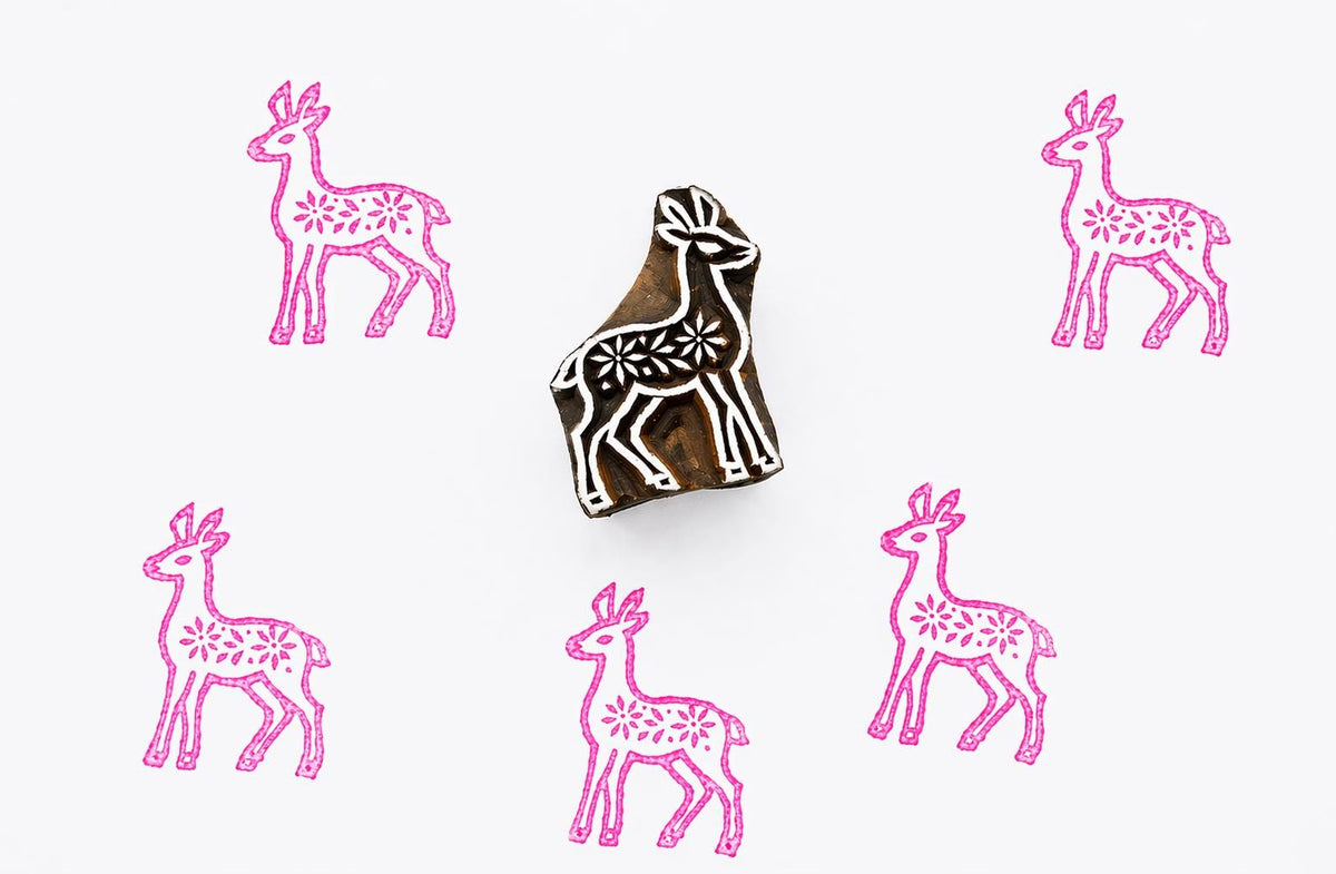 Hand carved wooden block stamp creating a Scandinavian folk style deer pattern with floral details in pink ink