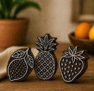 Hand carved wooden printing block set with lemon pineapple and strawberry stamps on rustic wooden surface
