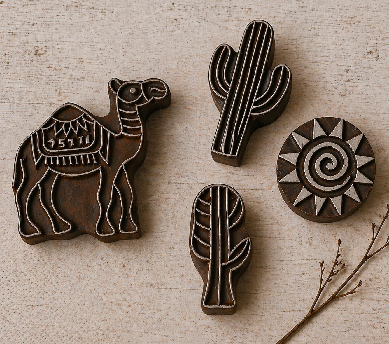 Hand carved wooden printing block set with camel, cactus and sun designs on neutral background