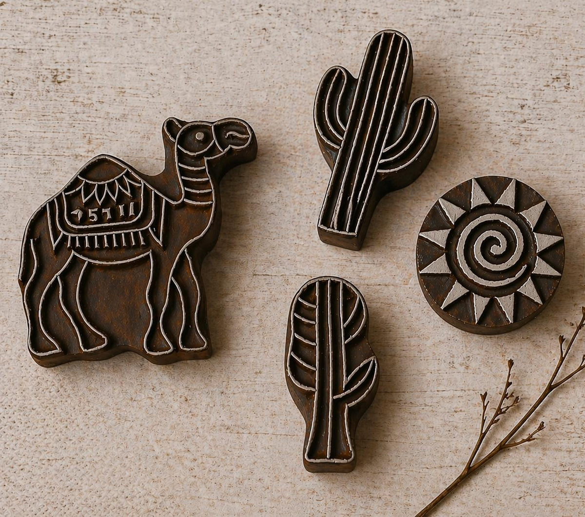 Hand carved wooden printing block set with camel, cactus and sun designs on neutral background