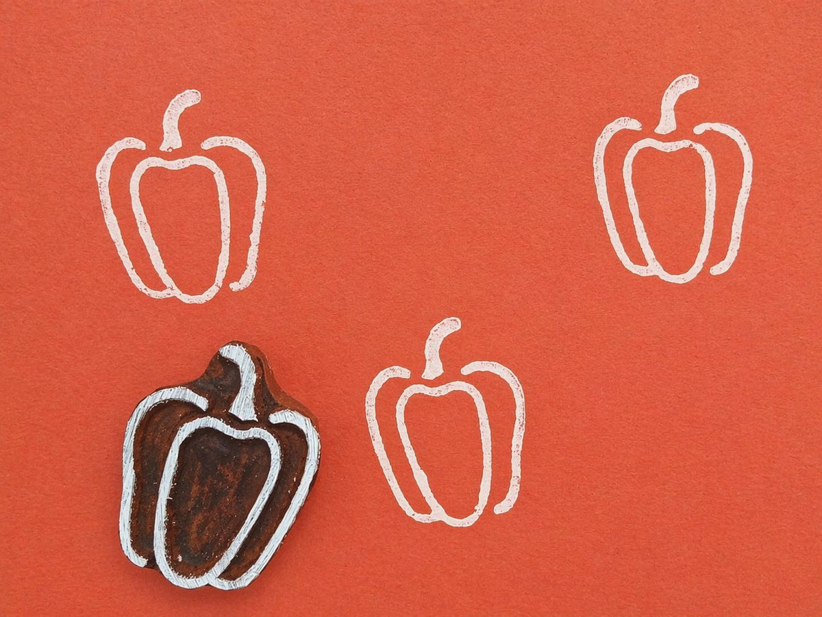 Hand carved pepper stamp printing white pepper pattern on orange background