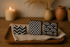 Set of three hand-carved wooden block stamps with geometric patterns displayed on neutral cloth with warm styled background