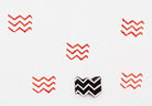 Hand-carved wooden zigzag stamp with red ink pattern printed on white background