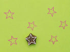 Star shaped wooden block stamp with repeated pink star prints on green background