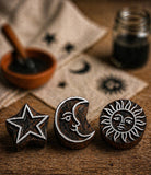 Hand carved wooden block print stamps featuring sun, moon and star designs on rustic textile background