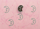 Crescent moon wooden stamp with repeating green moon prints on textured pink paper