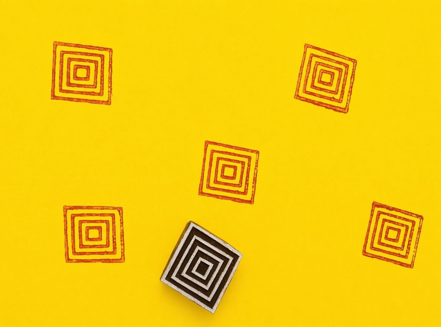 Concentric square wooden stamp creating repeating orange geometric pattern on yellow background