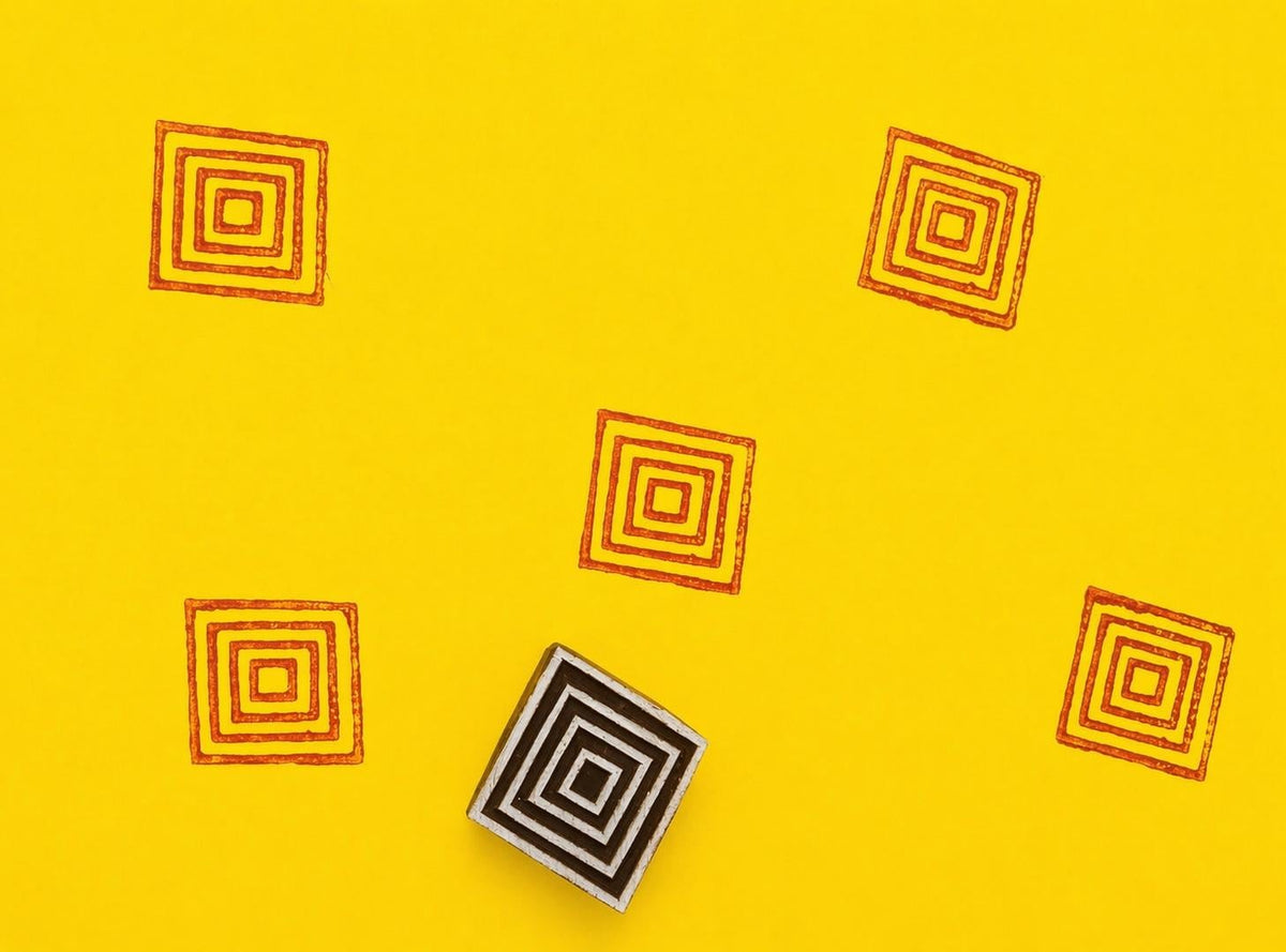 Concentric square wooden stamp creating repeating orange geometric pattern on yellow background