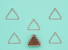 Wooden block stamp with step pyramid design shown with repeated printed pattern on teal background