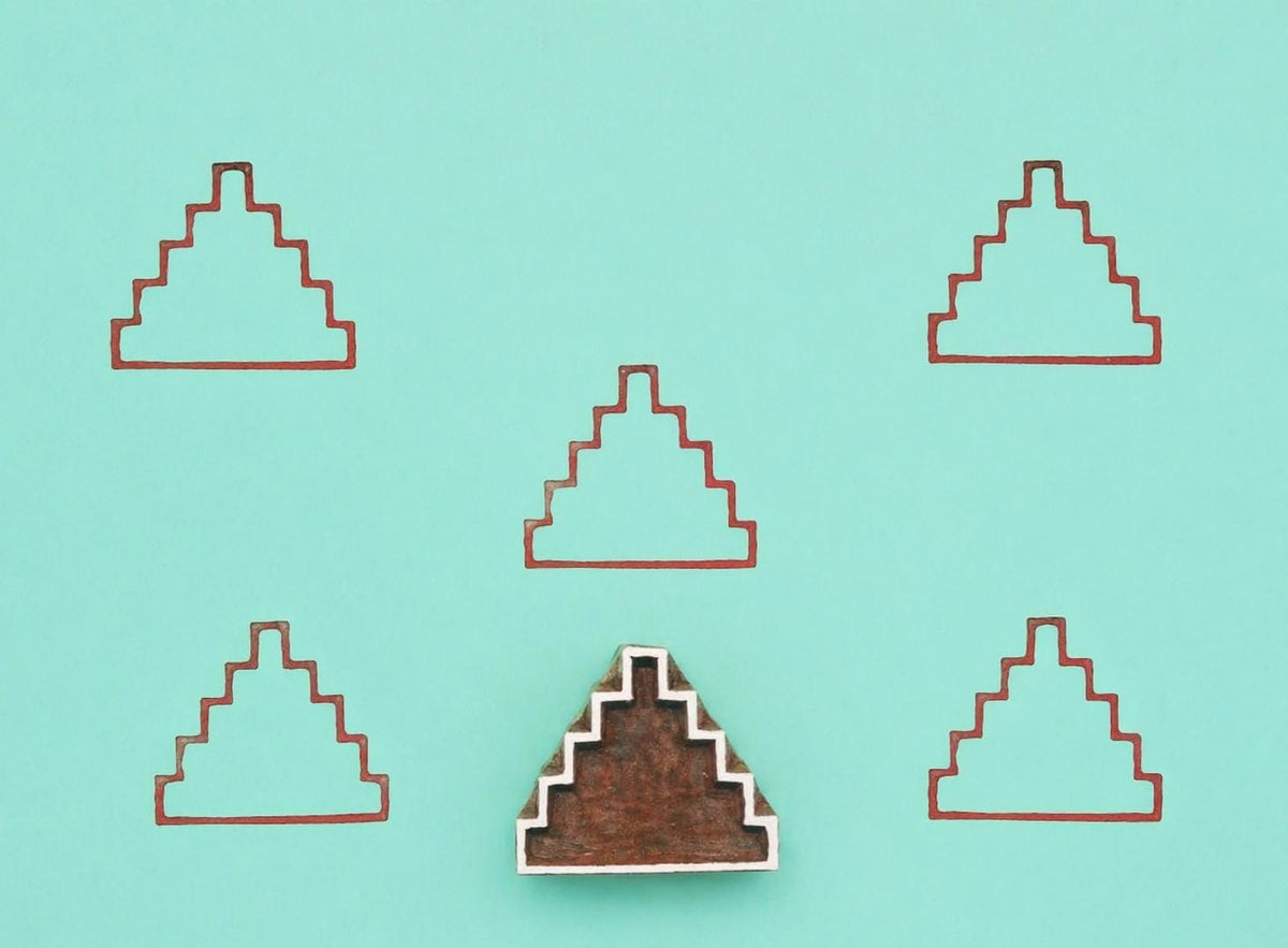Wooden block stamp with step pyramid design shown with repeated printed pattern on teal background