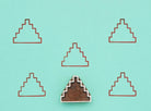 Wooden block stamp with step pyramid design shown with repeated printed pattern on teal background