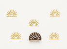 Wood block stamp with sunburst design and repeated golden prints on white background