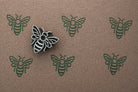 Repeating bee pattern printed in dark green ink using handmade wooden stamp on kraft paper
