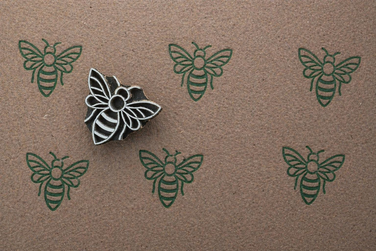 Repeating bee pattern printed in dark green ink using handmade wooden stamp on kraft paper