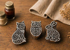 Hand carved wooden stamp set with Sentinel Fox, Moonwatch Owl and Meadow Hare on rustic table