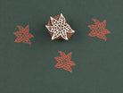 Hand carved wooden poinsettia block stamp printing intricate lace floral star pattern in red ink on dark green paper