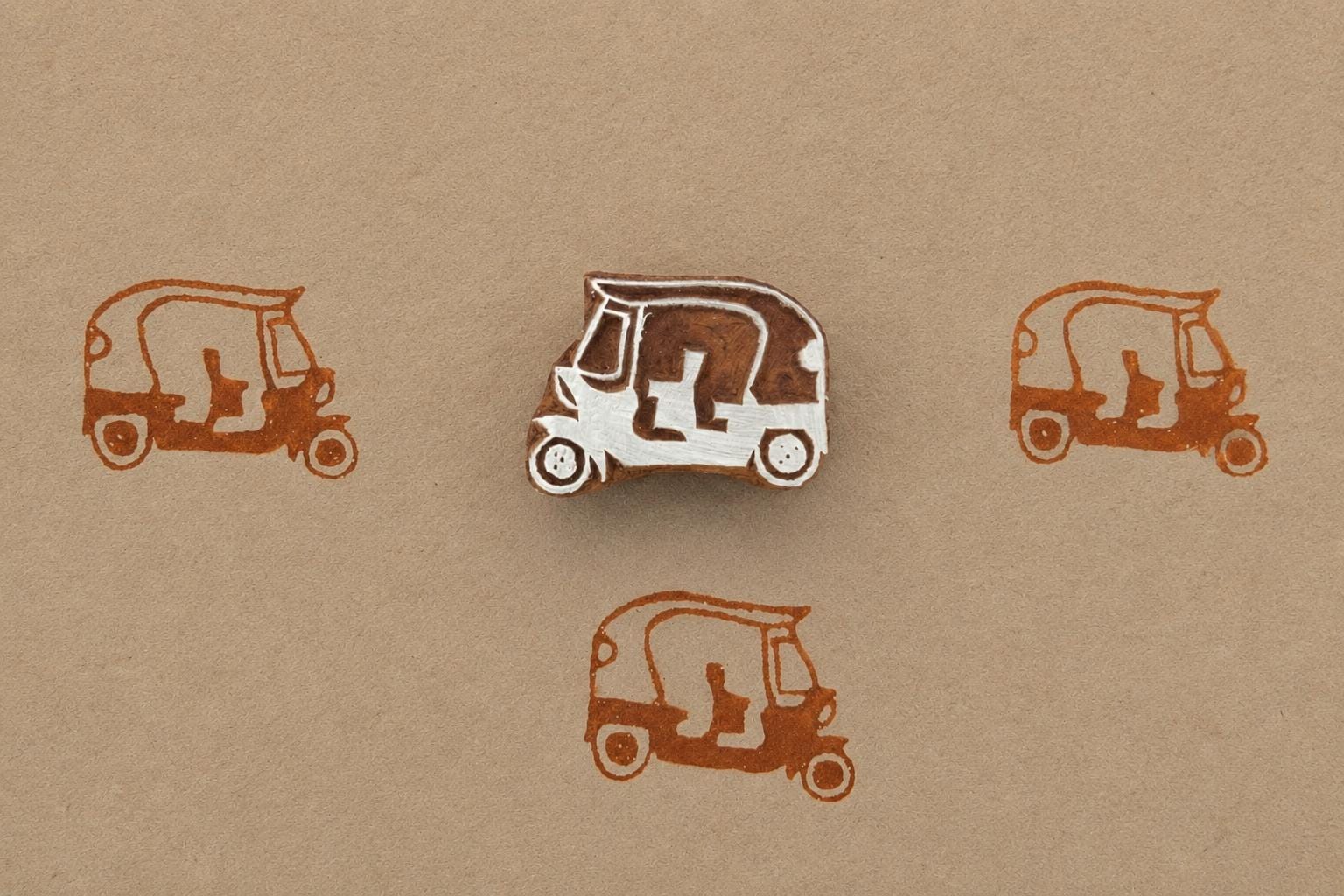 Hand carved wooden auto rickshaw block stamp printing tiny tuk tuk vehicle motif in brown ink on kraft paper