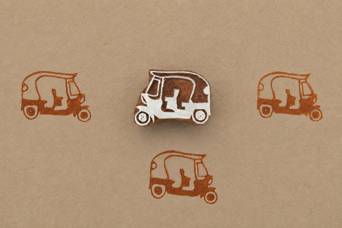 Hand carved wooden auto rickshaw block stamp printing tiny tuk tuk vehicle motif in brown ink on kraft paper