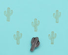 Hand carved wooden block stamp creating a minimalist linear cactus pattern in soft yellow ink on blue background
