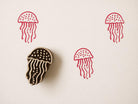 Hand carved wooden printing block with a jellyfish illustration for ocean themed fabric printing and marine surface patterns.