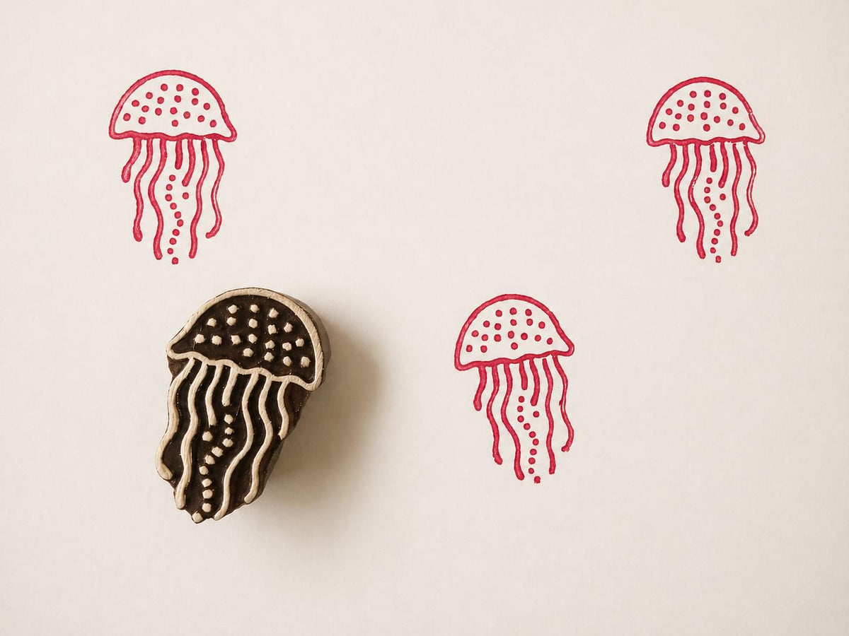 Hand carved wooden printing block with a jellyfish illustration for ocean themed fabric printing and marine surface patterns.