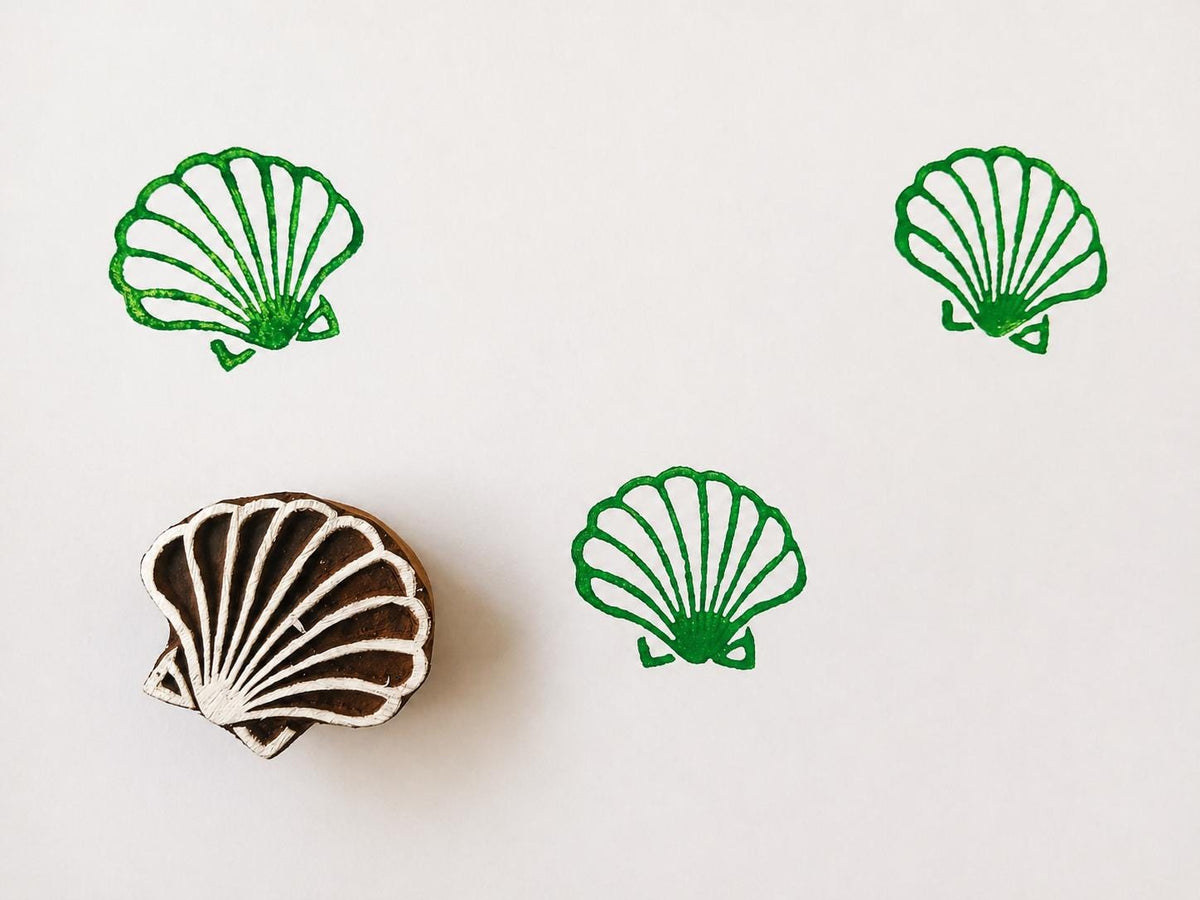 Hand carved wooden printing block with a scallop shell illustration for beach themed fabric printing and coastal craft projects.