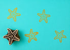 Hand carved wooden printing block with a starfish illustration for beach themed fabric printing and ocean inspired repeat patterns.
