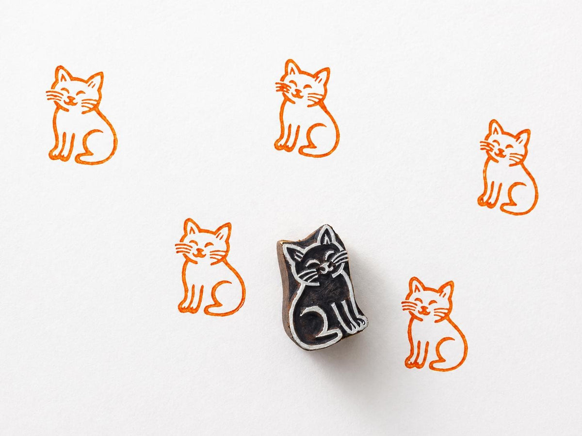 Hand carved wooden cat printing block with smiling feline design for fabric printing and pet themed craft projects.