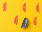 Hand carved wooden tropical frond block stamp printing delicate feather leaf motif in pink ink on yellow background