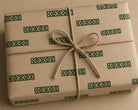 Gift wrapped package decorated with repeating hand printed geometric border motifs created using a hand carved wooden block stamp on kraft paper