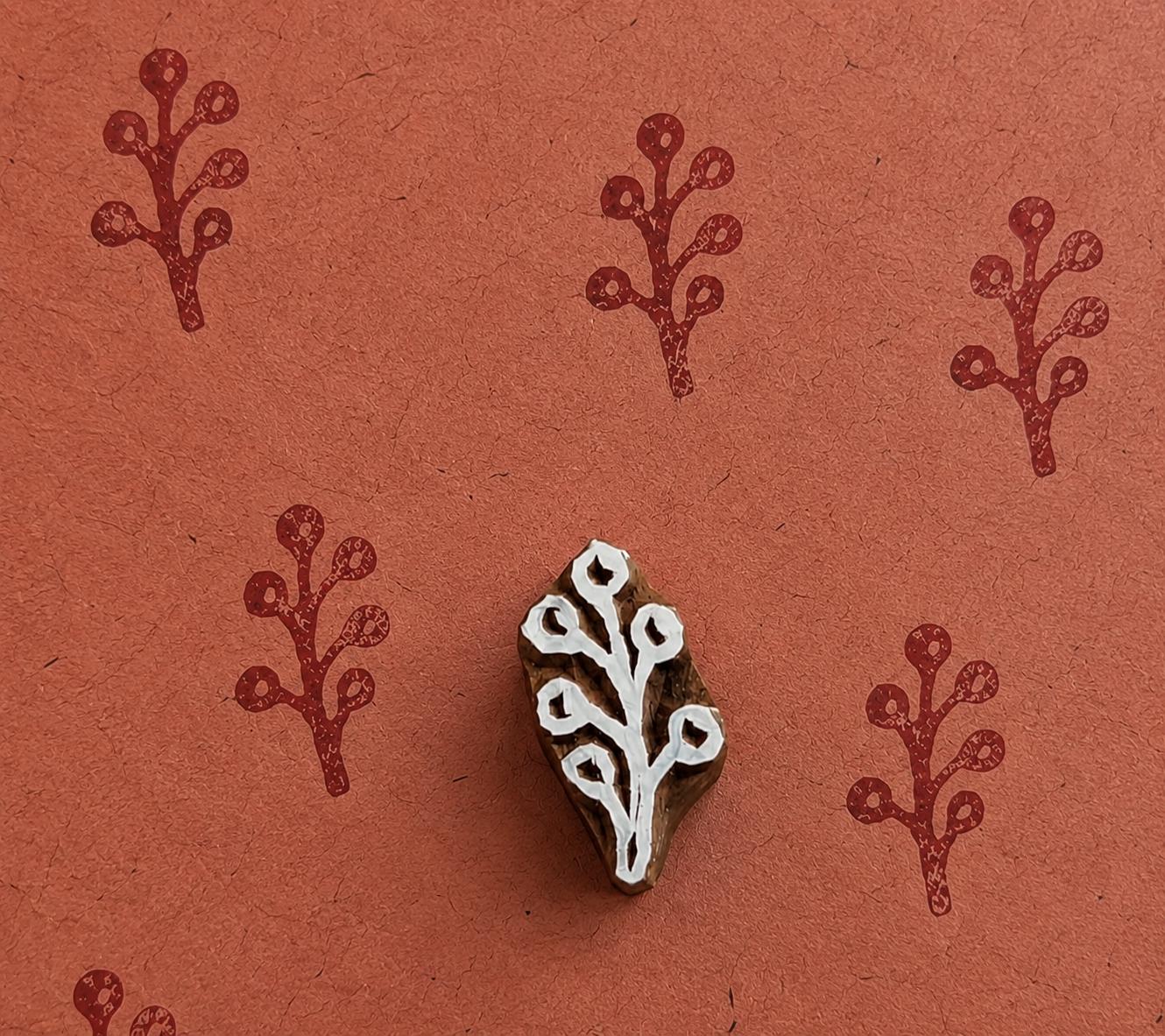Tiny hand carved winter berry sprig block stamp with repeating botanical berry branch impressions on handmade paper
