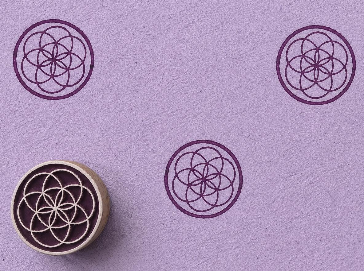 Hand carved wooden printing block featuring an overlapping sacred circle geometry motif stamped repeatedly on lavender paper.